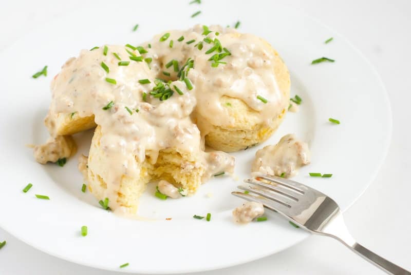 A side shot of cheddar cheese biscuits and sausage gravy and topped with chives