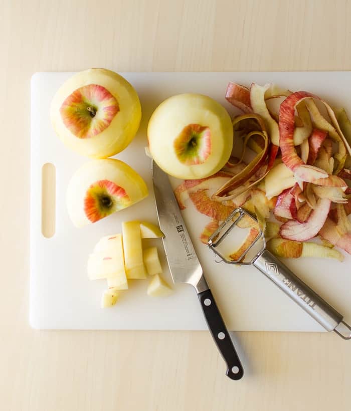 Apples on a cutting board getting cut into slices and peeled