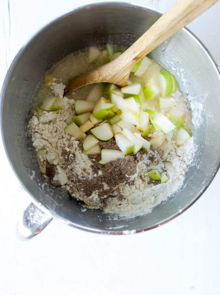 Cardamom Apple Muffins ingredients in a large mixing bowl with a wooden spoon