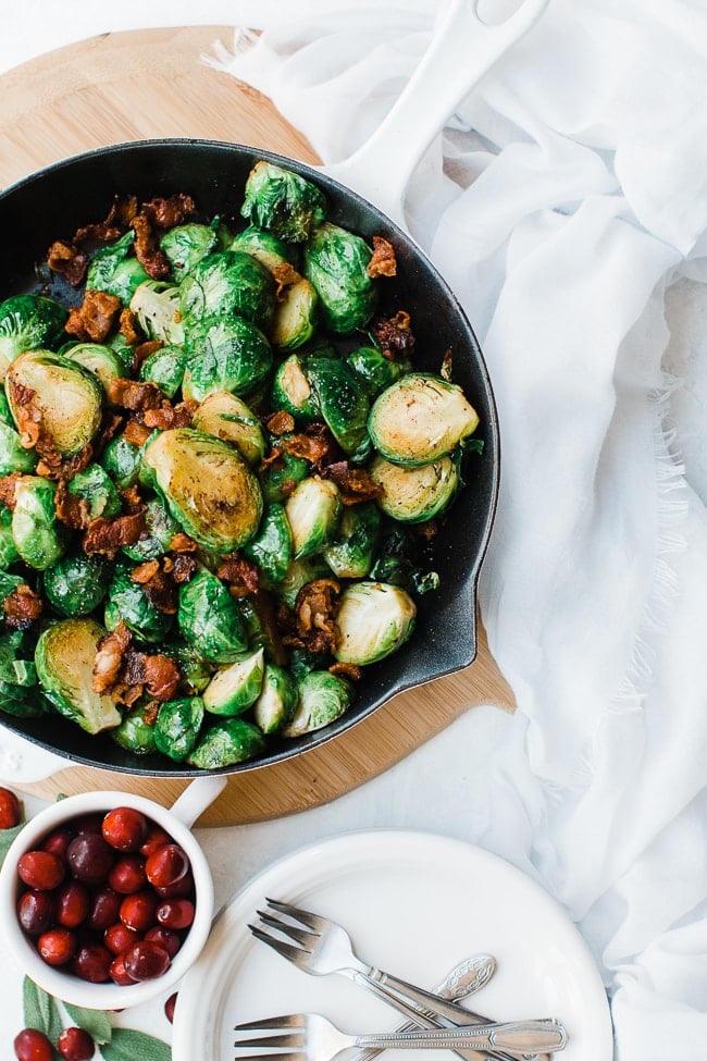 Brussel sprouts with bacon and garlic in a white skillet.
