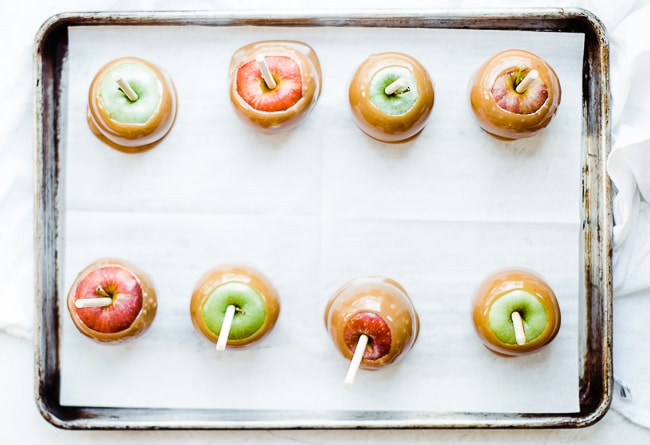 8 apples lined on parchment sheet with caramel
