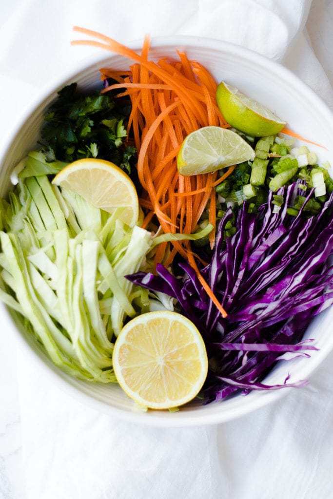 A close up of shredded and chopped vegetables in a bowl for making citrus slaw