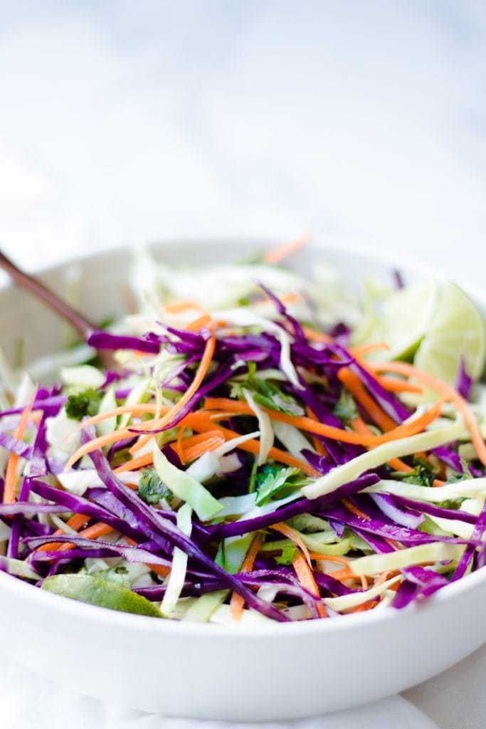 A side shot of citrus slaw in a white bowl