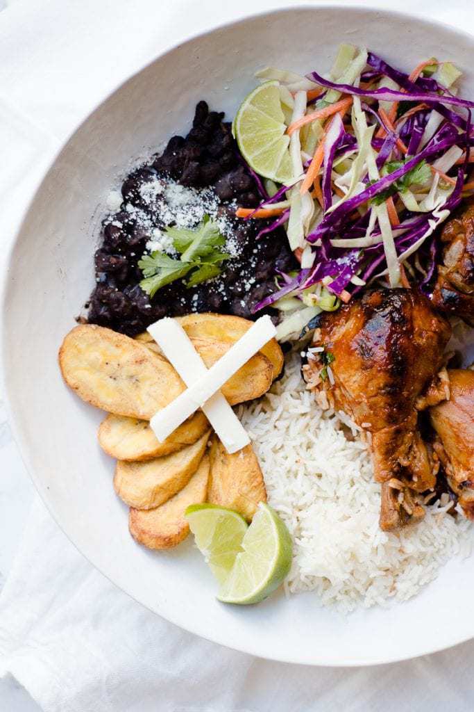 An overhead shot of a bowl with chicken, rice and citrus slaw on the side