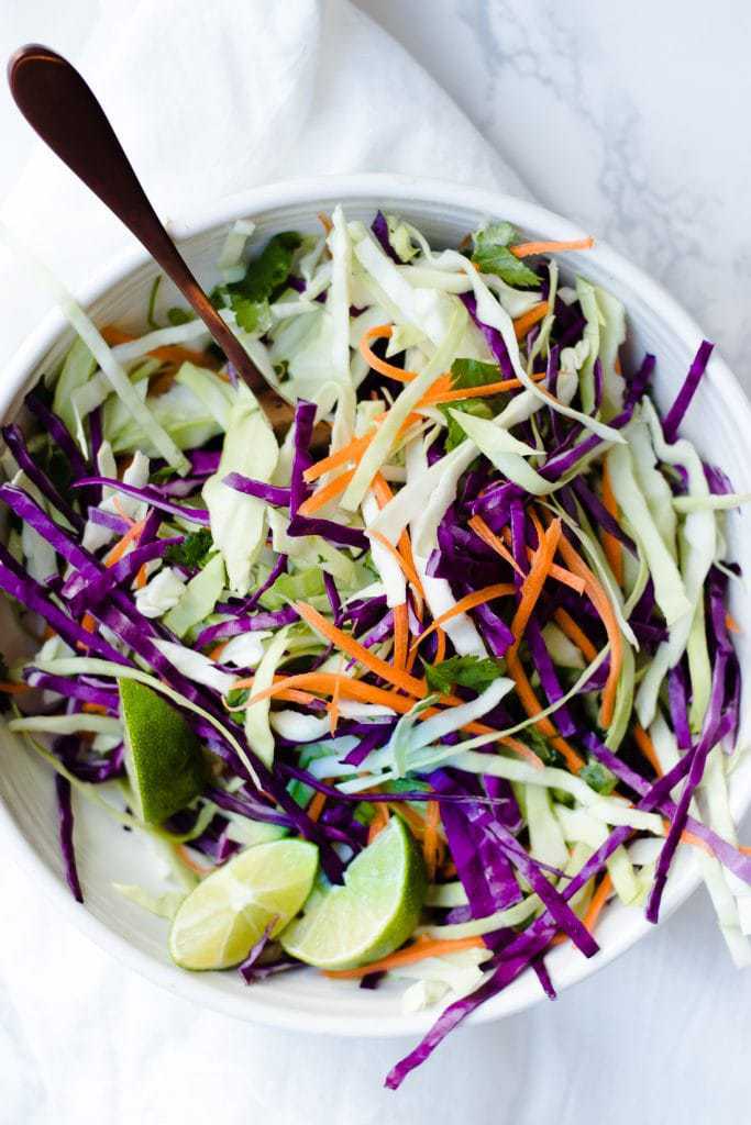An overhead shot of citrus slaw in a white bowl
