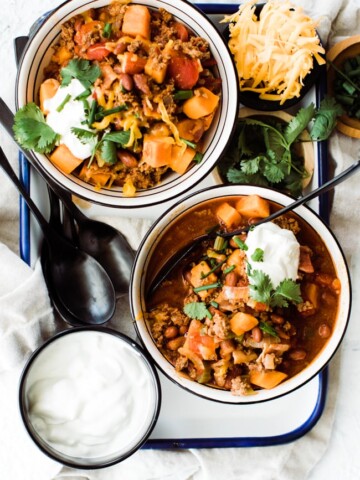 two bowls of chili topped with sour cream and cilantro
