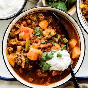 one bowl of chili with sour cream and cilantro