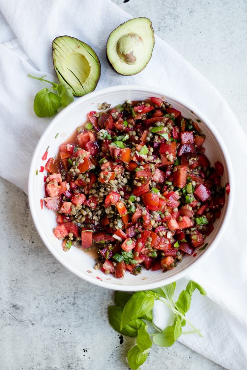 Lentil Bruschetta Recipe in big bowl, surrounded by halved avocado and basil