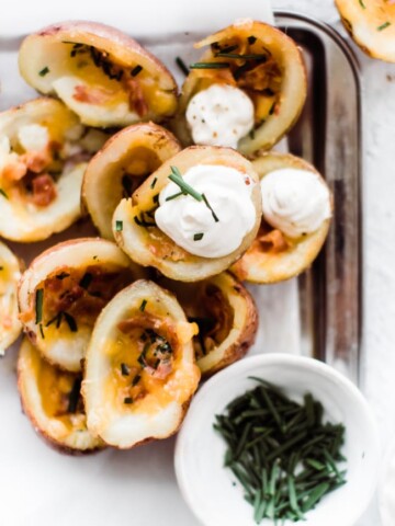 potato skins on a tray with sour cream