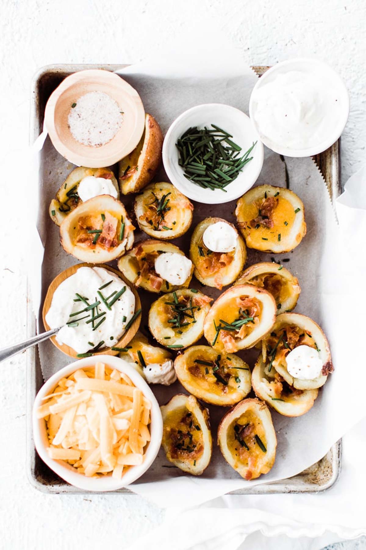 Potato skins on a tray with sour cream.