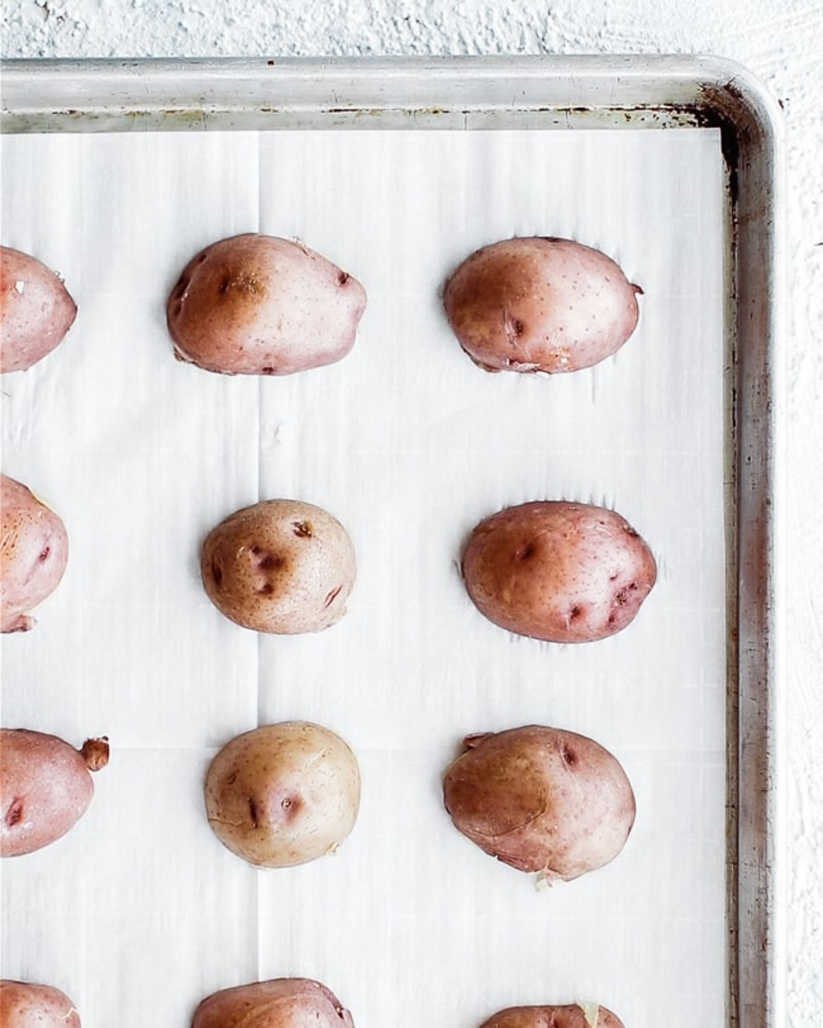 Halved potatoes face down on a tray.
