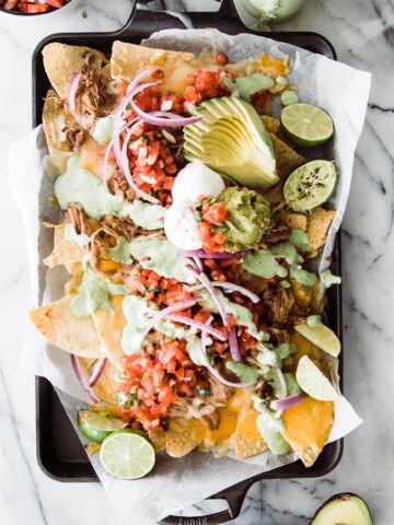 nachos on tray with toppings and creamy jalapeno sauce