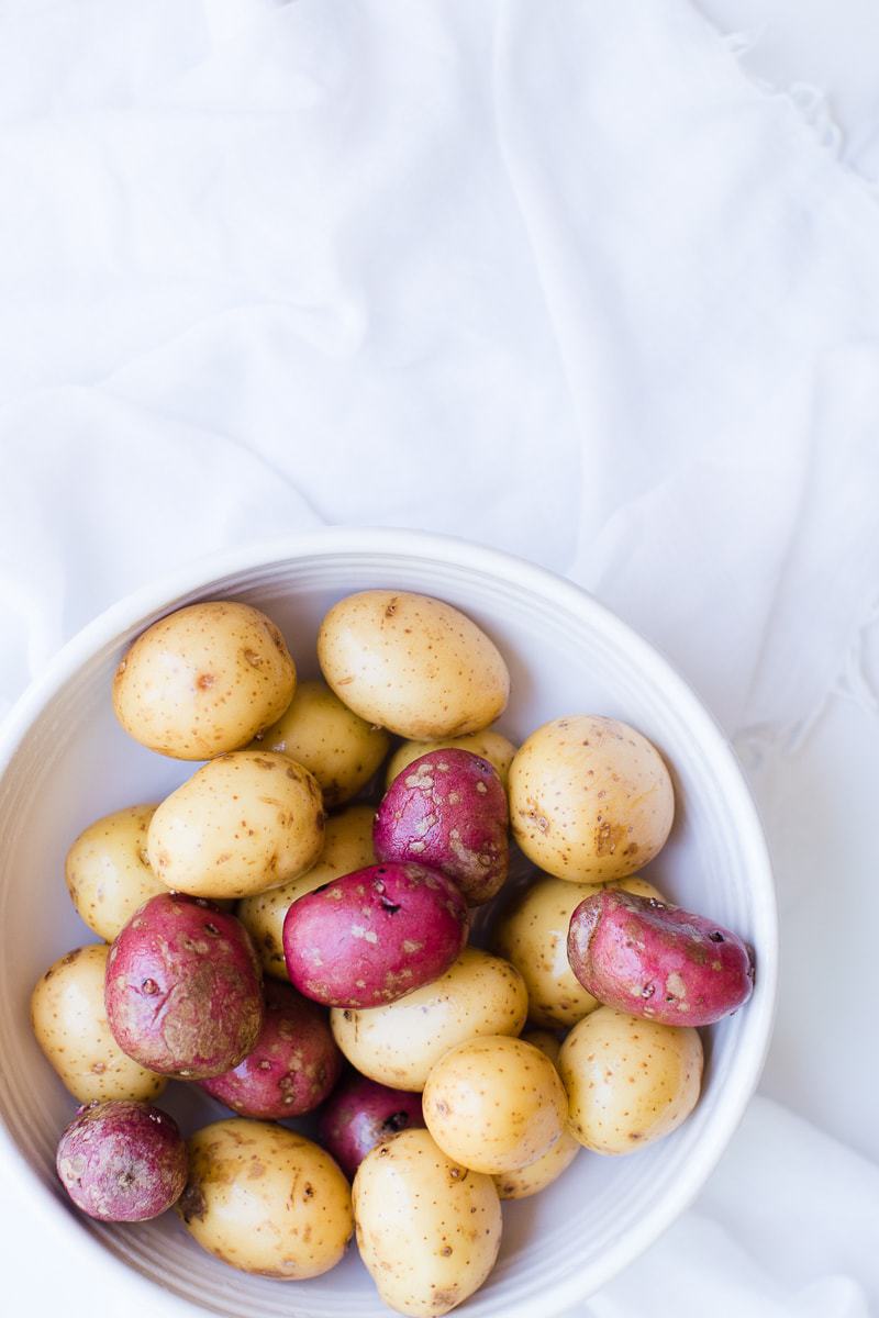 pre-cooked, unpeeled potatoes in a white bowl