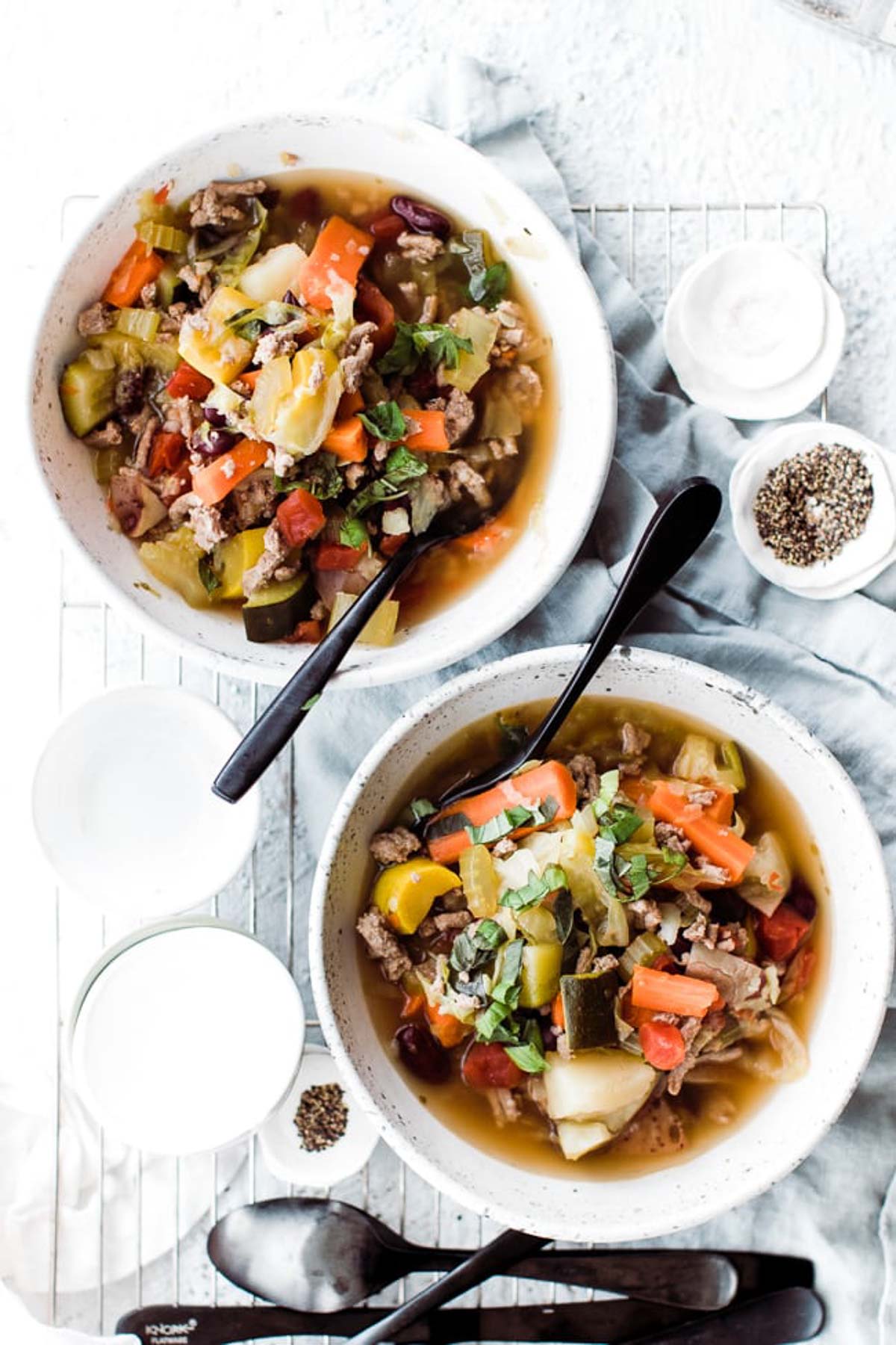 Overhead image of two bowls of weight loss soup on the table with spoons.