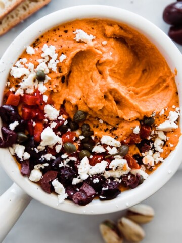 bowl of roasted red pepper hummus with feta olives on top