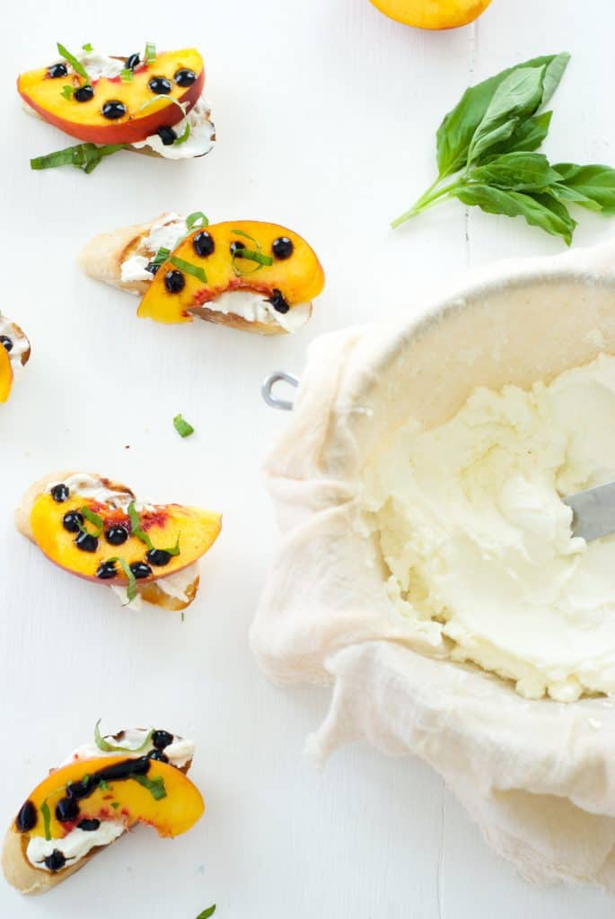 Peach, Ricotta, and Basil Crostini on a white surface with homemade ricotta at the side