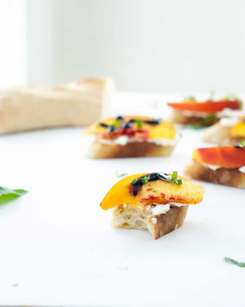 A Peach, Ricotta, and Basil Crostini with a bite out