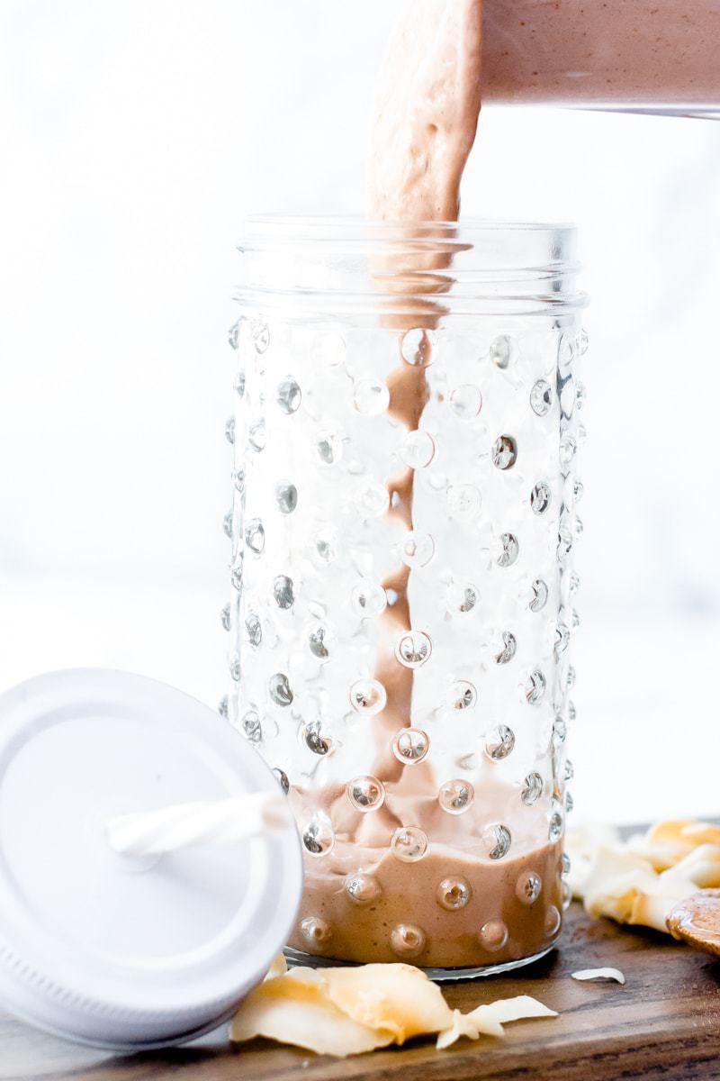 chocolate coconut protein shake getting poured into a glass
