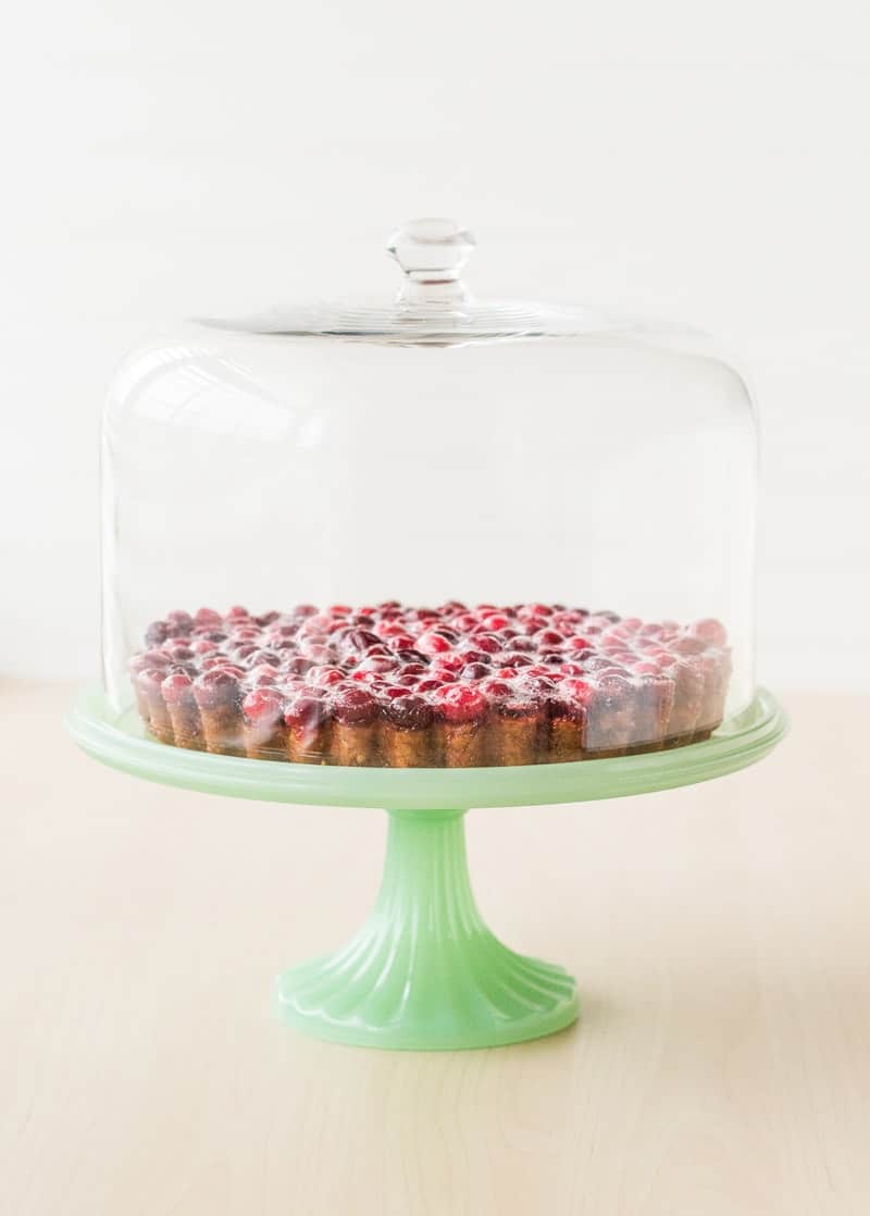 Christmas Cranberry Tart on a green cake stand with a glass cover