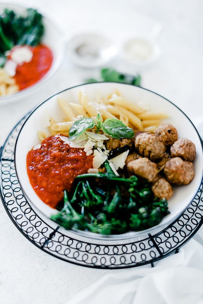 Italian bowl full for meatballs, pasta, and broccoli.