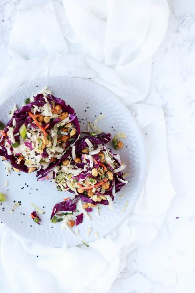 Copycat Peanut Slaw served in purple cabbage wedge on a white plate