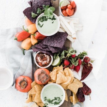 board with bowls of dip and veggies and chip