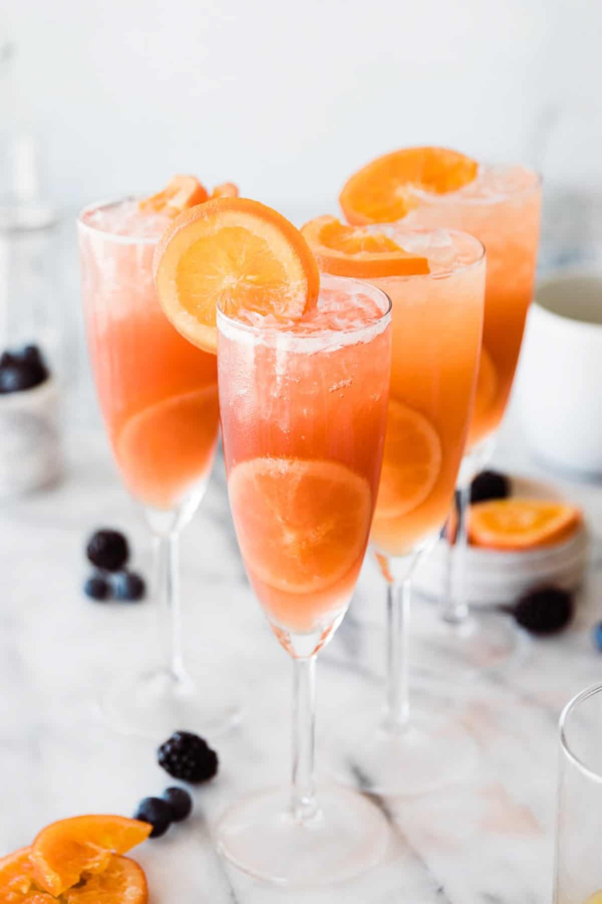 Cranberry mimosa mocktails on the table with orange slices on the glass.