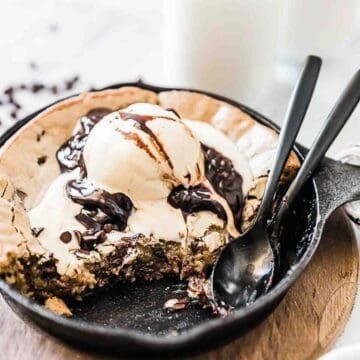Cast Iron Skillet Cookie also called a pizookie is topped with ice cream and chocolate sauce.