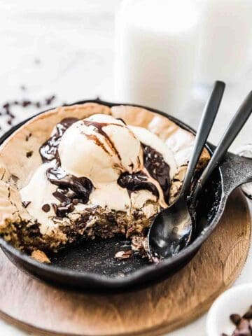 Cast Iron Skillet Cookie also called a pizookie is topped with ice cream and chocolate sauce.