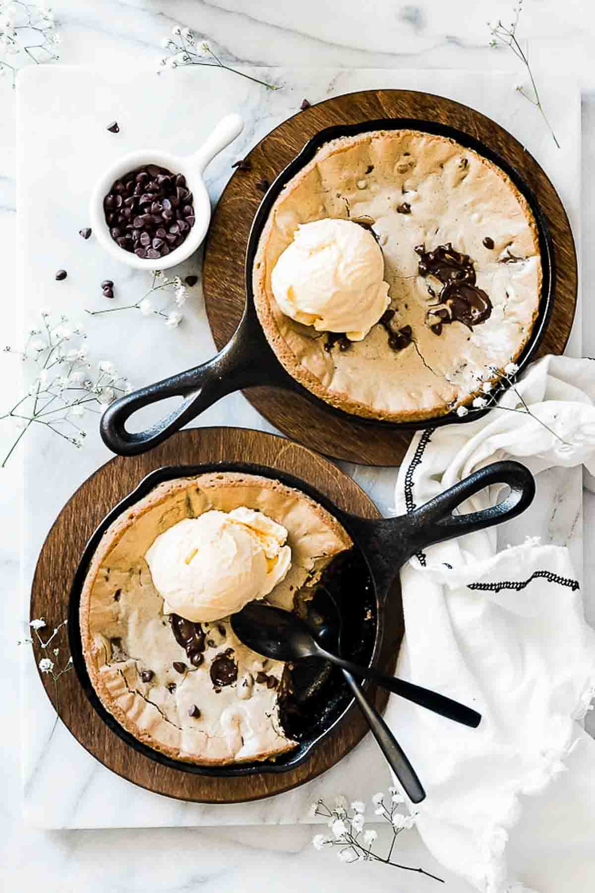 An overhead shot of baked pizookies garnished with ice cream, and chocolate chips.