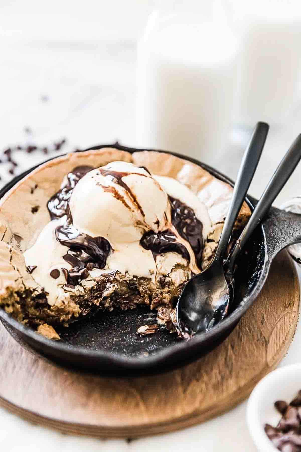 Cast Iron Skillet Cookie in a cast iron skillet topped with ice cream and chocolate sauce.