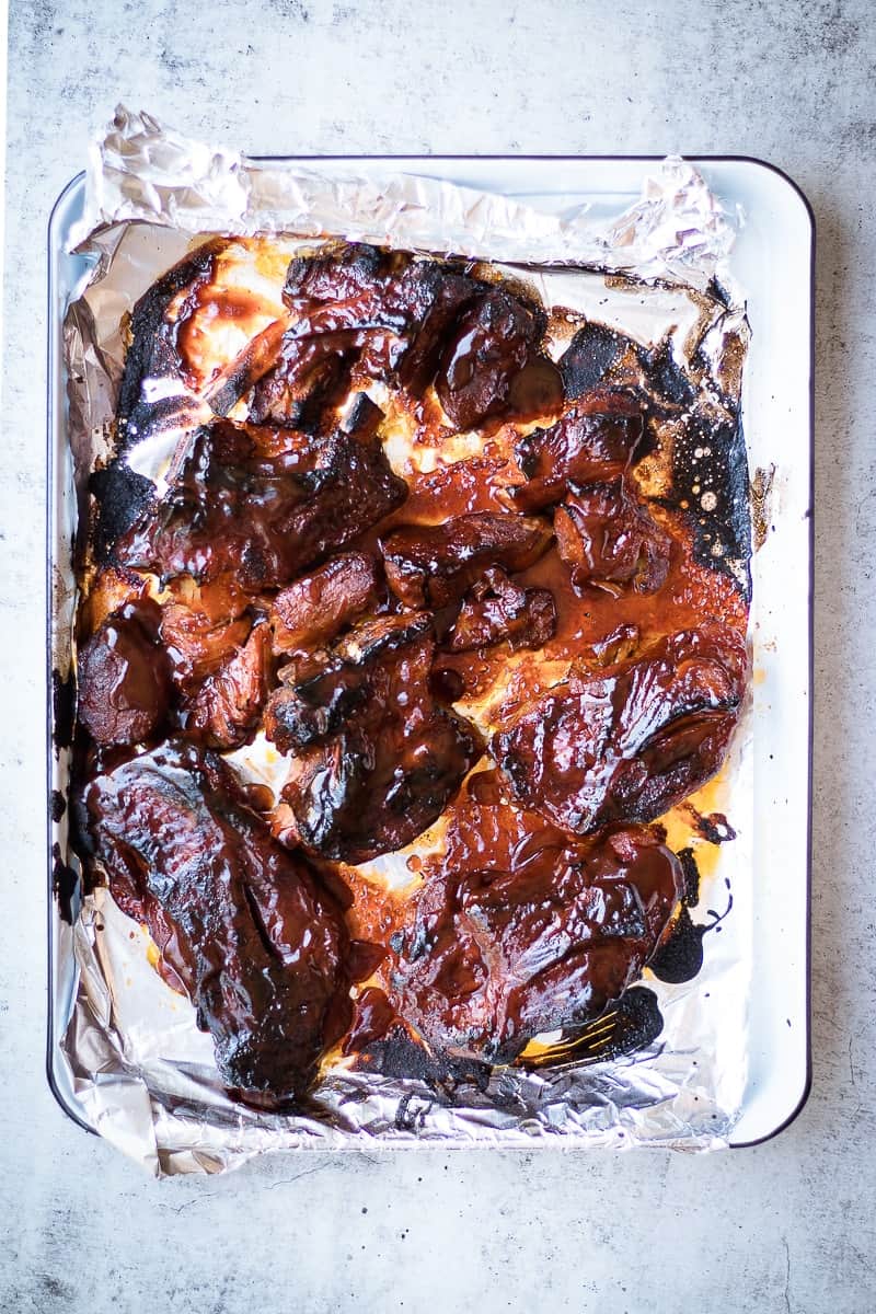 An overhead shot of country ribs on a baking tray covered in a sticky glaze