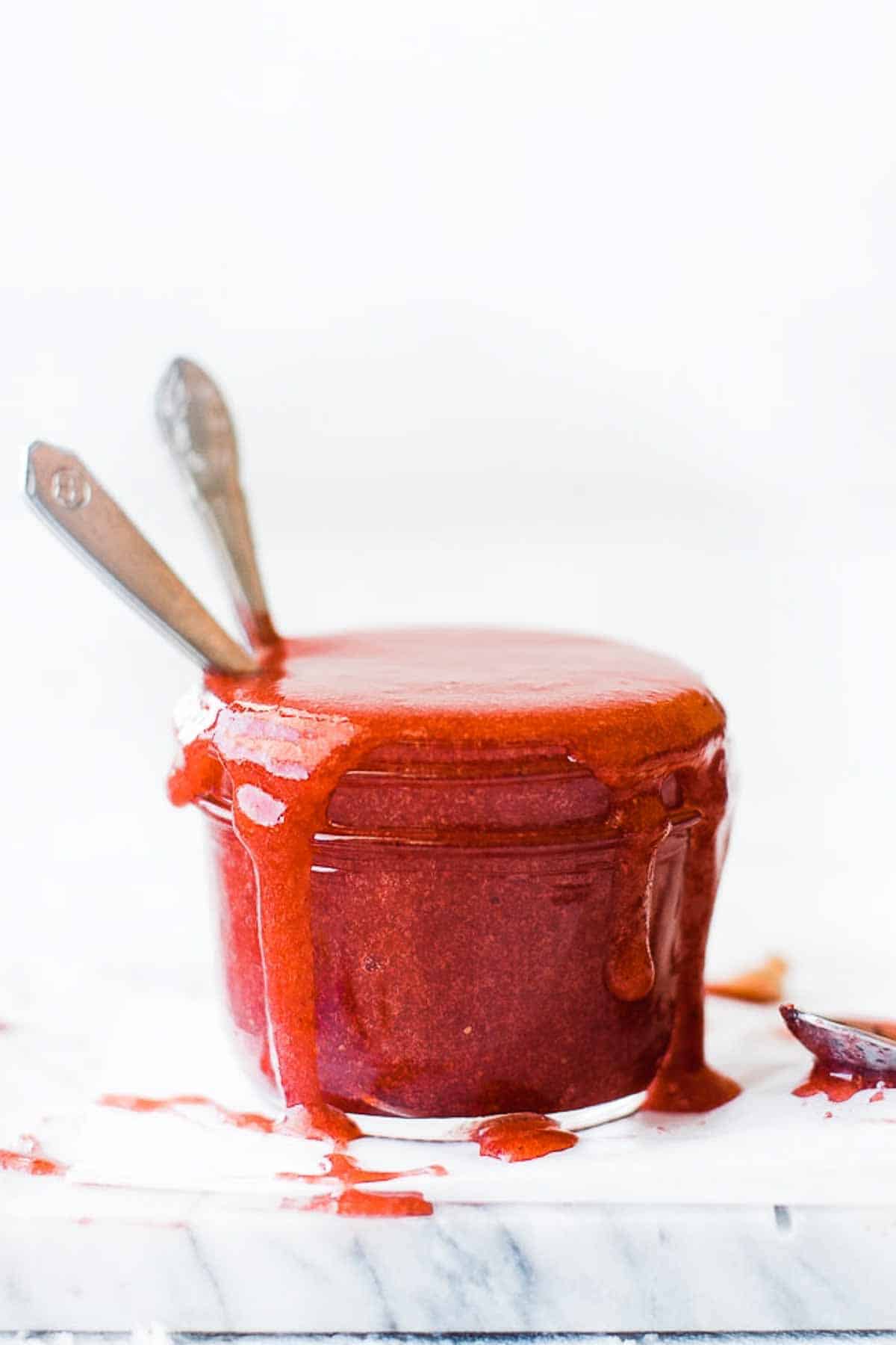 A small jar of homemade jam with two spoons.