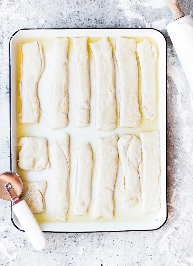 doughy breadsticks on baking sheet with butter