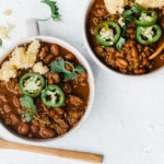 Best Chili Con Carne in white bowls atop a brown cutting board.
