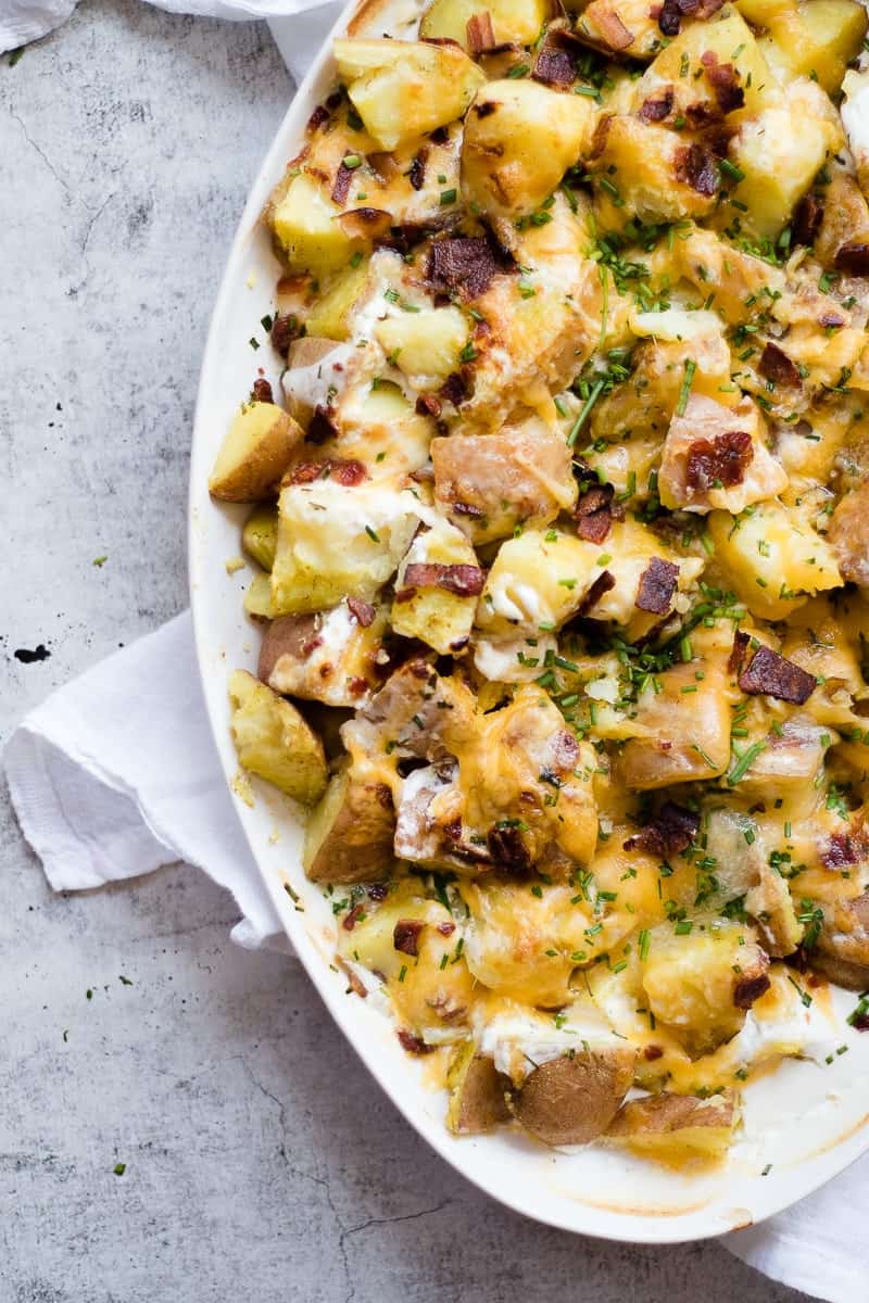 A close up photo of a cheesy potatoes recipes with melted cheese and bacon on top