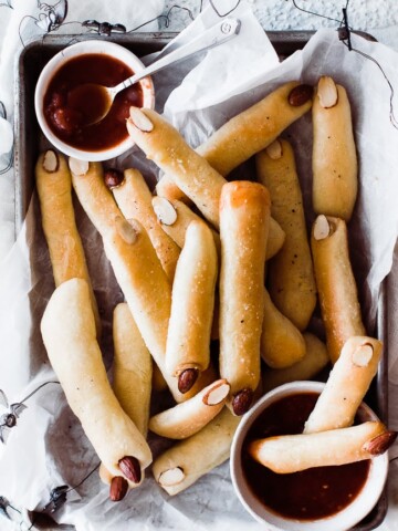 tray of witch finger breadsticks and two bowls of marinara sauce