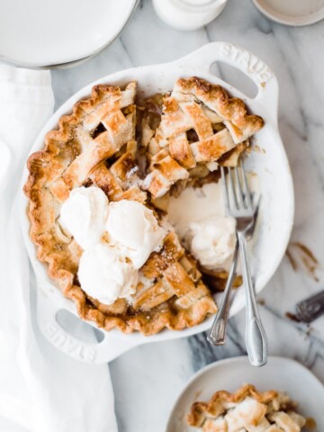 An overhead of a homemade apple pie from scratch with scoops of ice cream on top.