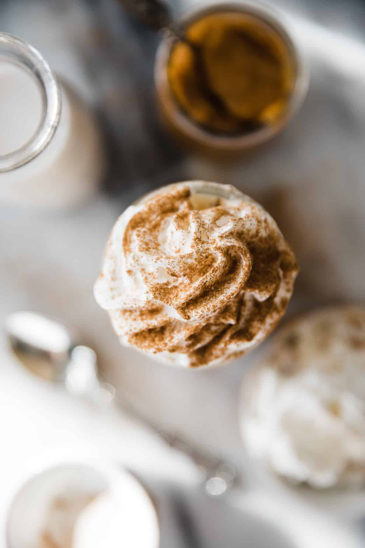 Top down photo of swirled whip cream on jar with cinnamon dusting. 