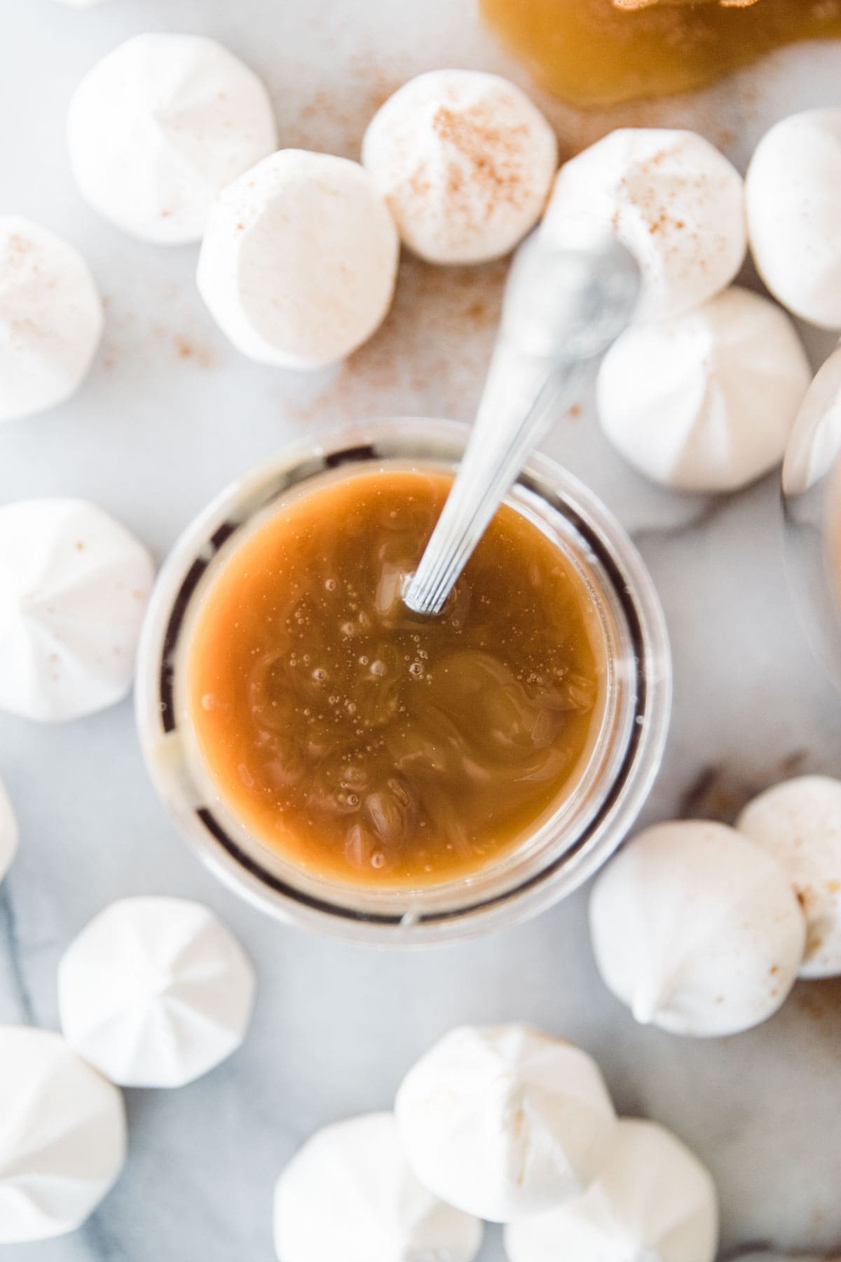 small glass with a spoon dipping into caramel sauce