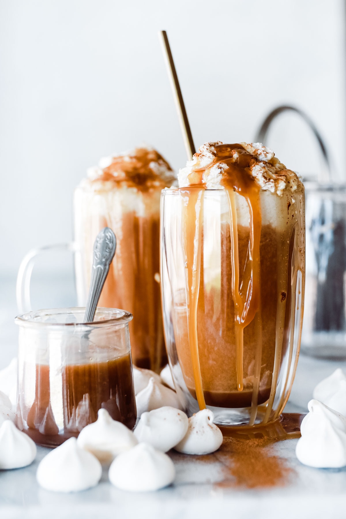 glass mug with caramel colored drink and whip cream and caramel dripping on it