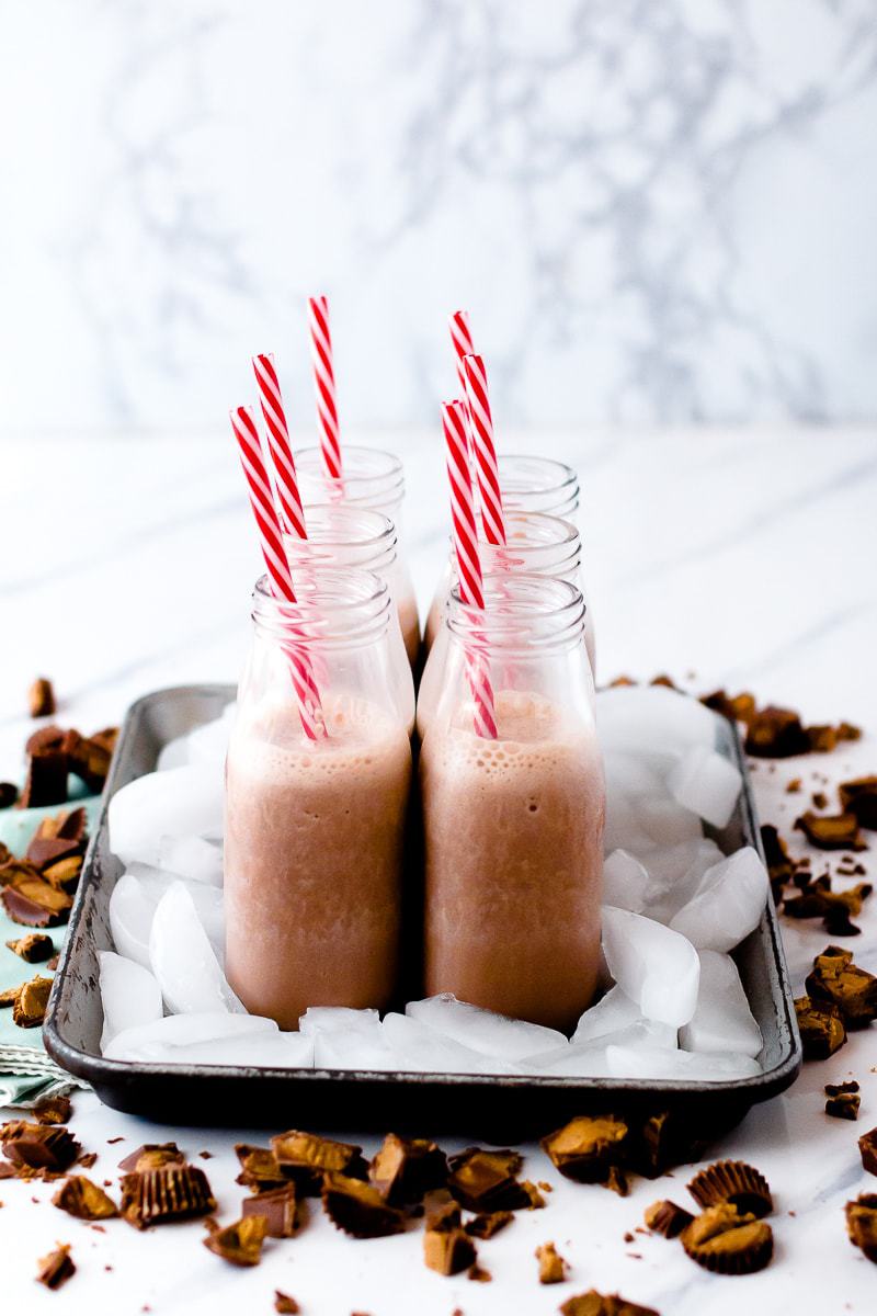 Kids Peanut Butter Cup Protein Shake in glass bottles with ice and red straws