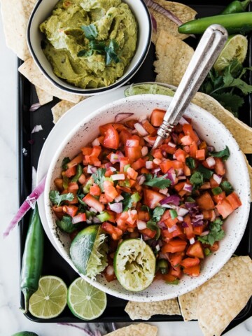 bowl full of fresh pico de gall and a lime