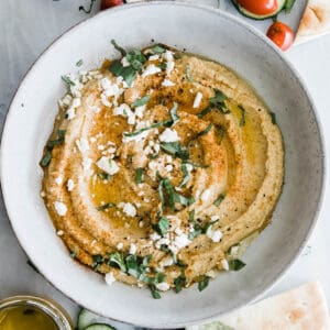 one large bowl of creamy hummus with feta and basil topping.