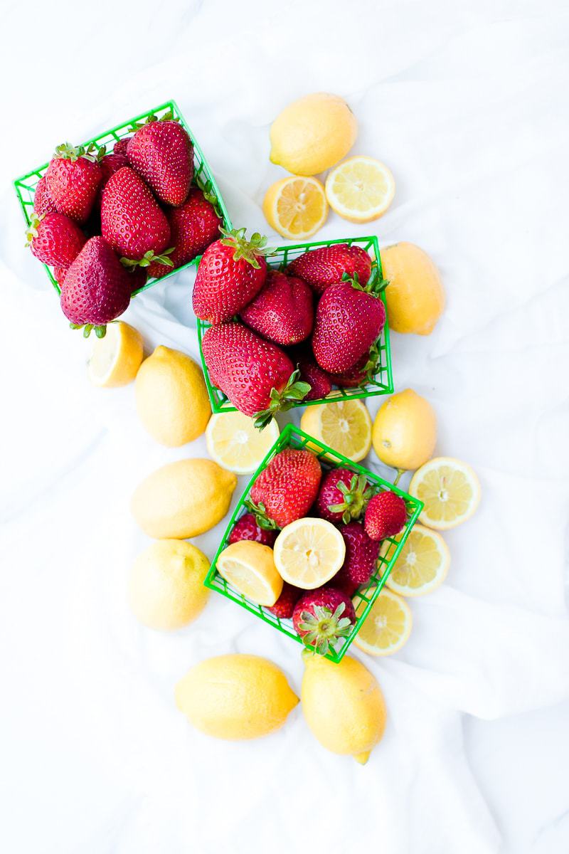 An overhead shot of fresh strawberries and lemon used to make homemade strawberry lemonade