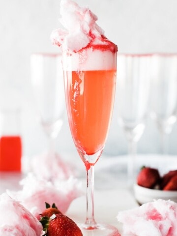 single champaign glass with sparkling strawberry lemonade and cotton candy as garnish on top