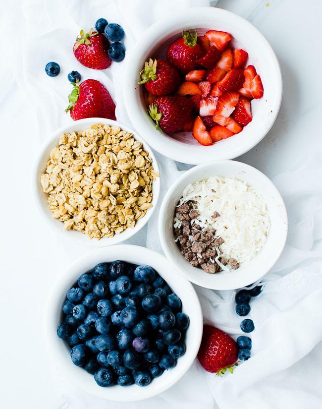 diced strawberries, granola, coconut and chocolate chips, blueberries in bowls for toppings