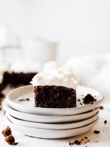 frosted chocolate zucchini cake on a stack of white plates