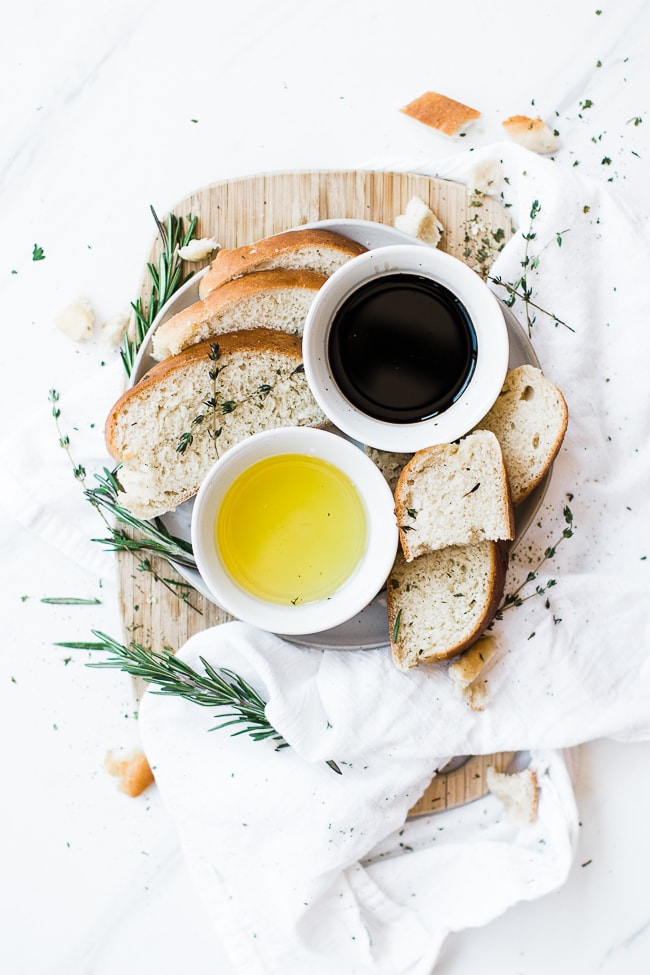 sliced bread on cutting board with balsamic vinegar and olive oil