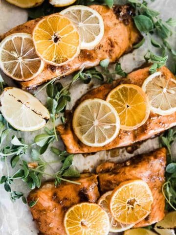 A closeup of citrus salmon on a baking tray, The salmon has citrus slices on top of it.